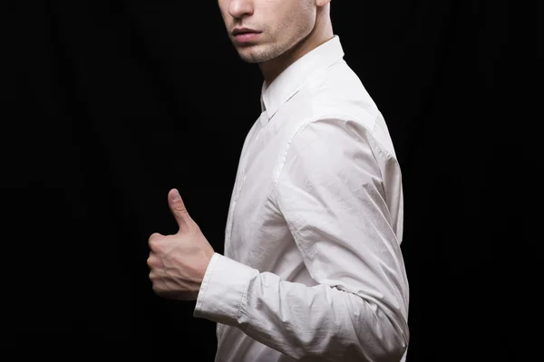 On a black background turned sideways young man in a white shirt