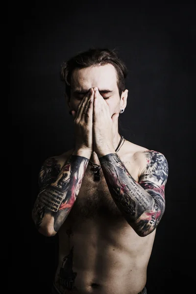 Portrait of a man with naked torso and tattooes
