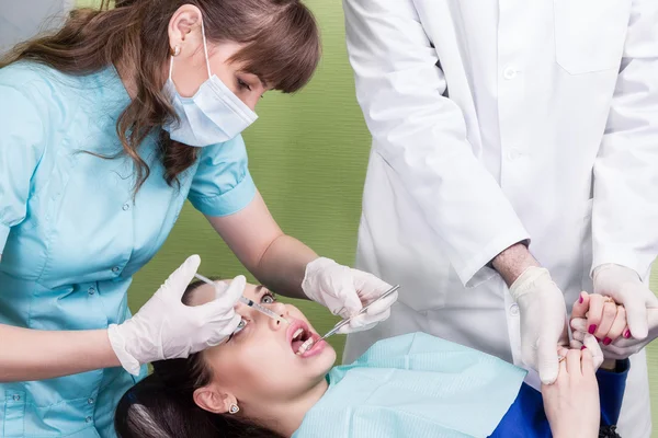 Dentist making anaesthetic injection to female patient