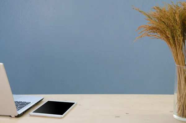 Office table with notepad, computer and dry tree. View from abov