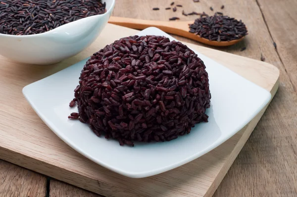 Black Rice cooked on white plate and black rice grains organic.