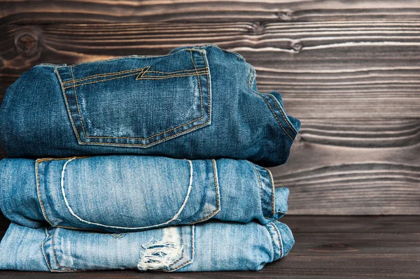 Fashionable clothes. pile of jeans on  wooden background