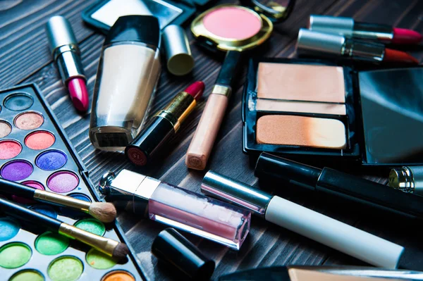 Various makeup products on dark background. Cosmetics make up artist objects: lipstick, eye shadows, eyeliner, concealer, powder, tools for make-up