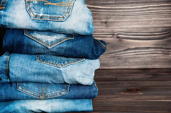 Pile of  jeans clothes on wooden background.