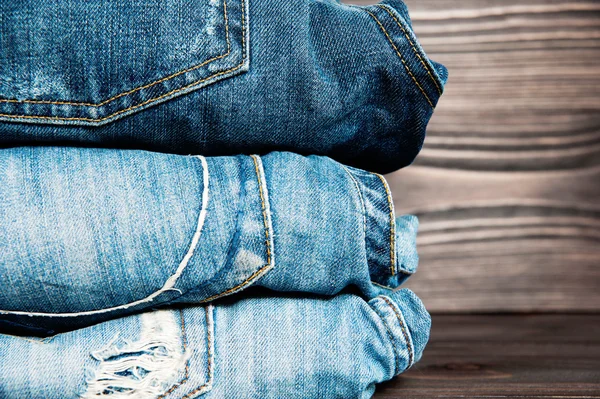 Pile of jeans clothes on wooden background.