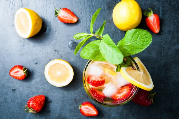 Strawberry lemonade and ingredients - strawberry, lemon, dark stone background.