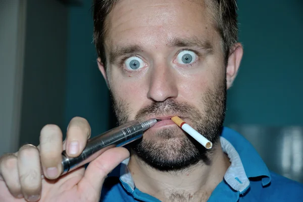 Man smoking e-cigarette, regular cigarette. Make funny face