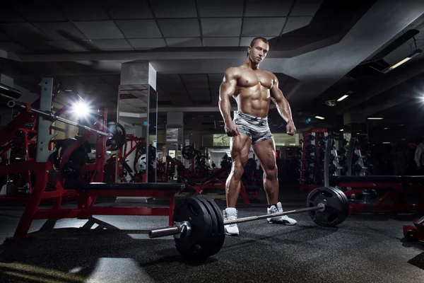 Very power athletic guy standing with barbell, workout in sport