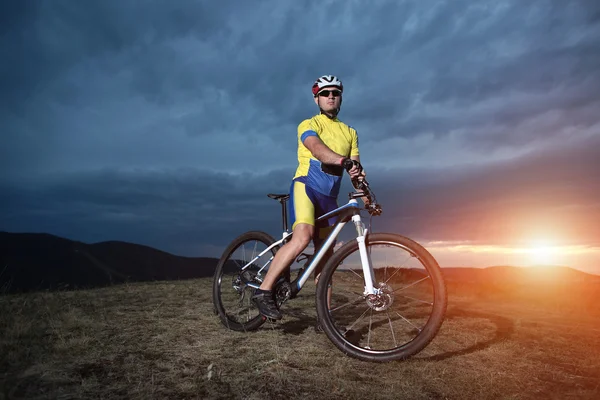 Mountain Bike cyclist posing on background outdoor hill. Sunset