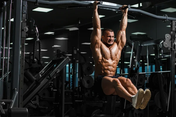 Athlete muscular fitness male model pulling up on horizontal bar