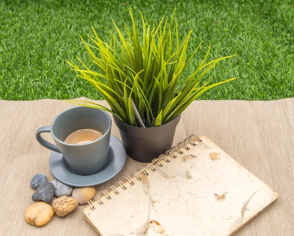Cup of coffee, green plant and notebook