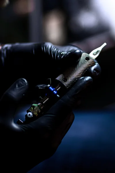 Tattoo artist  which make tattoo. Master works on professional  machine and in sterile  black gloves.