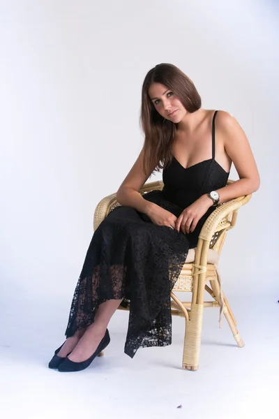 Beautiful Russian girl in a black dress ,sitting in a chair, looking ahead