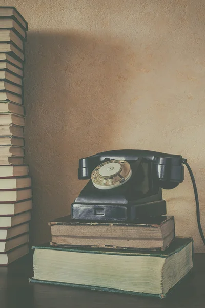 Old black phone and a stack of books