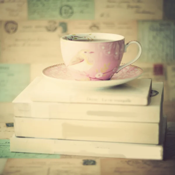 Cup of tea on books and letters on wall