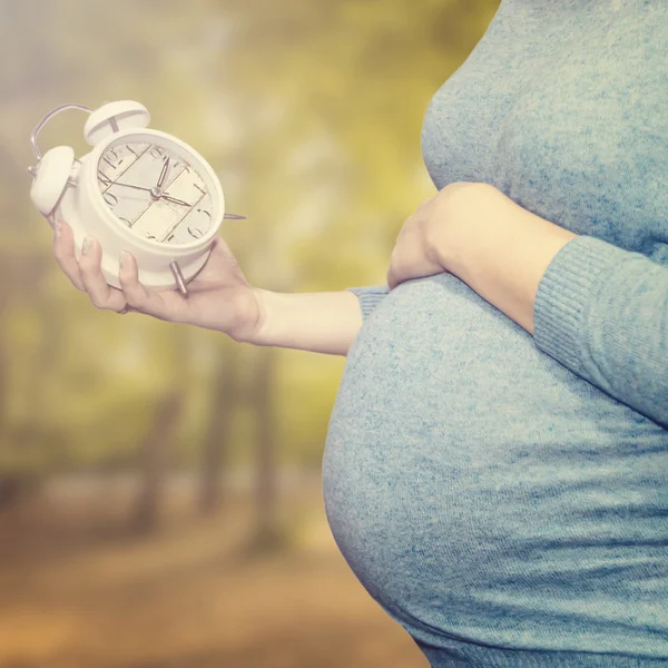 Pregnant woman looks at the clock