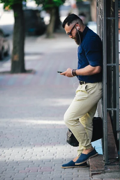 Bearded man standing and listening to music