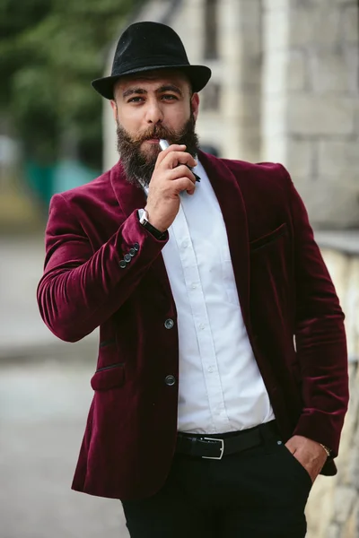 Rich man with a beard smokes electronic cigarette