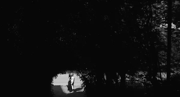 Couple jumping in the end of tunnel with trees
