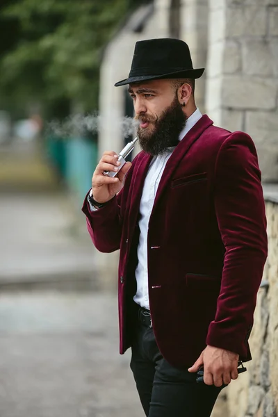 Rich man with a beard smokes electronic cigarette