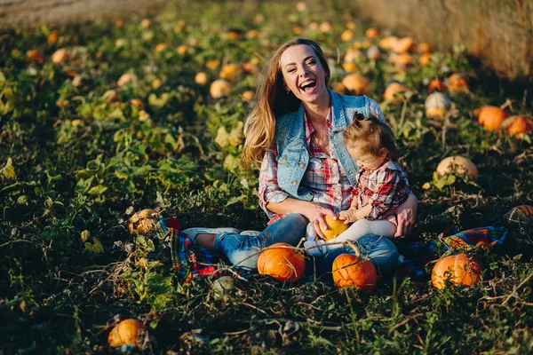 Mother and daughter on a field with pumpkins