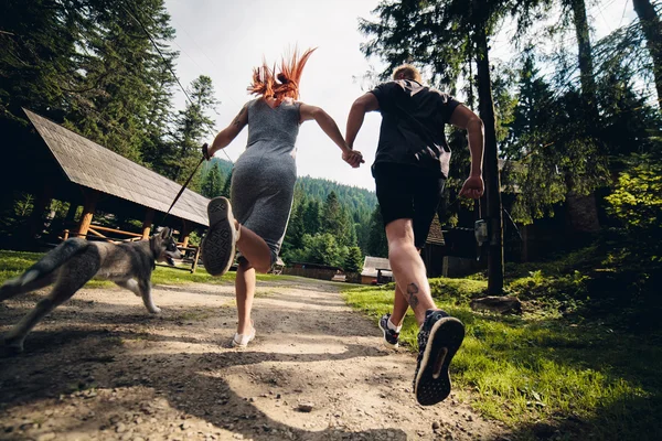 Couple runs on road in the nature with dog