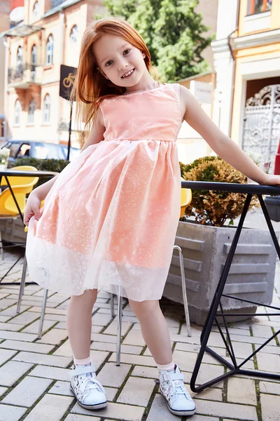 Small baby girl pretty kid happy childhood wear fashion dress sneakers walk run on the street cafe restaurant bright hair color cute smile building chair summer dance daughter
