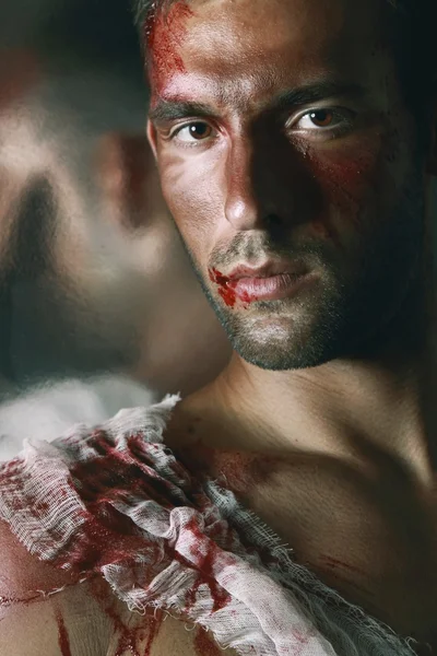 Portrait of handsome masculine bleeding man with a Blood on his shoulder Face and lips wearing jeans and watch who praying and look like Catholic