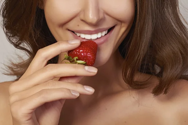Beautiful girl with Perfect smile eat red strawberry. white teeth and healthy food