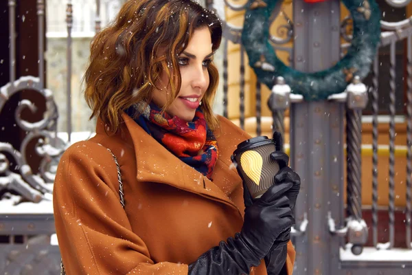 Woman with cup of coffee walk on snow street Christmas New Year