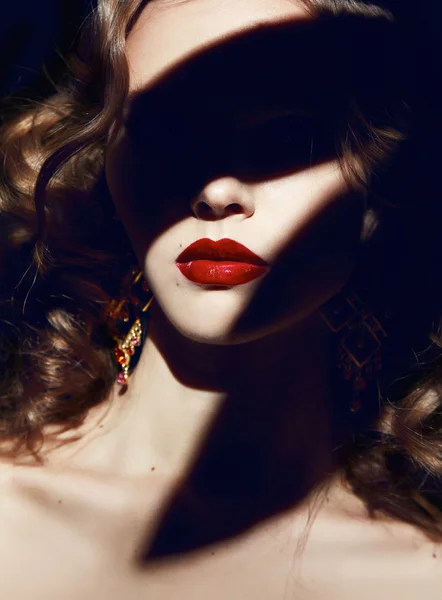 Beautiful blonde curly hair makeup red lips in the shadows