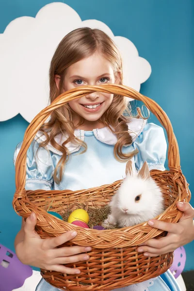 Little girl with basket with color eggs and white Easter bunny