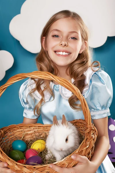 Little girl with basket with color eggs and white Easter bunny