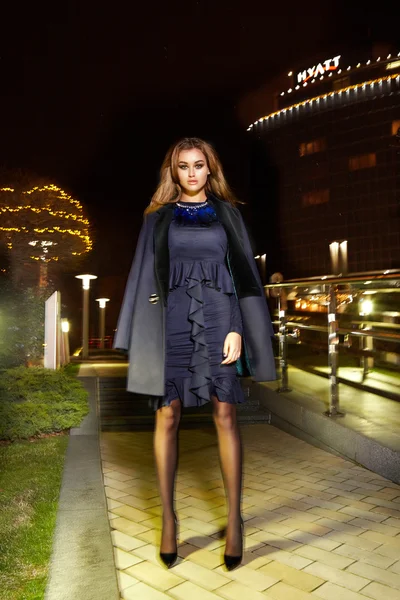 Beautiful young sexy blonde wearing evening makeup in elegant fitting dress fashionable stylish expensive fur coat walk night street lights evening hand  handbag luxury rich life going party concert