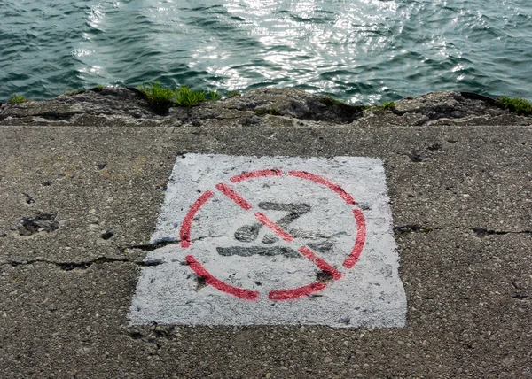 No Swimming Sign Painted on Crumbling Sidewalk