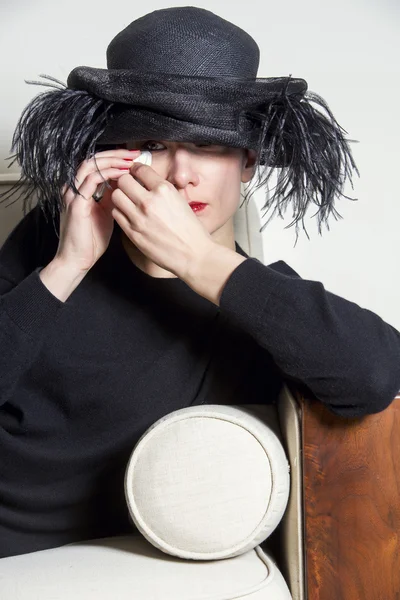 Portrait of a woman with black dress and hat looking sad