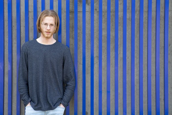 Young man with red long hair in front of blue wall