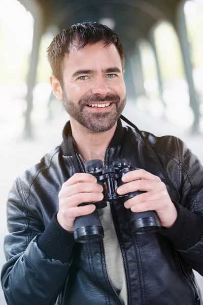 Man holding binoculars and smiles