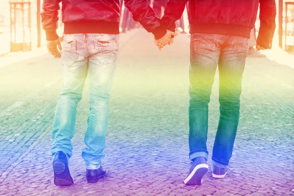 Two men holding hands with the rainbow colors for gay pride