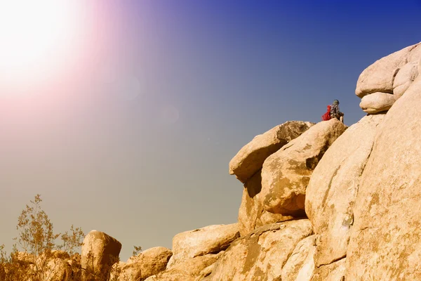 Man sitting on top of rocks in the desert