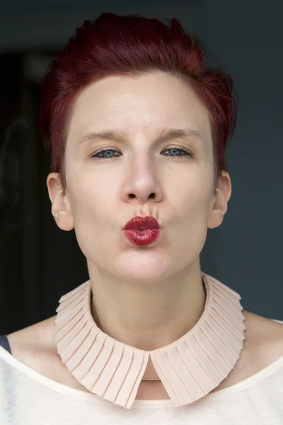 Portrait of red-haired woman giving a kiss