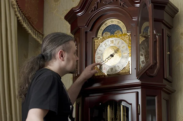 Man adjusts analog old clocks