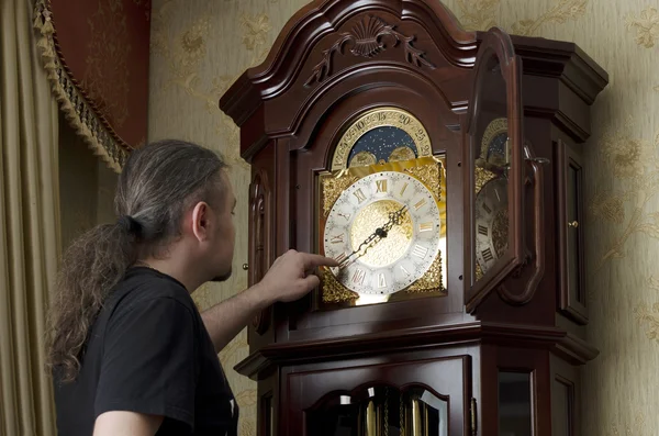 Man adjusts analog old clocks