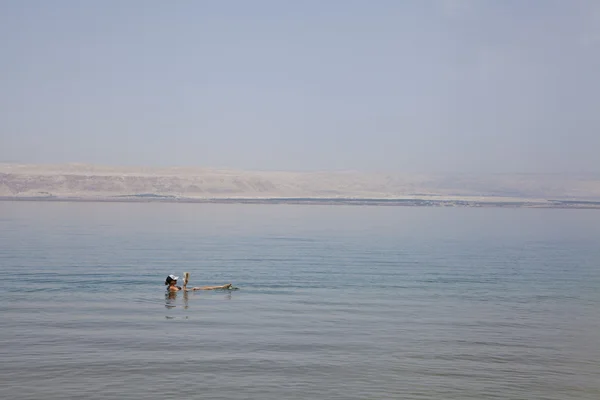 Young woman reads a book floating in the waters