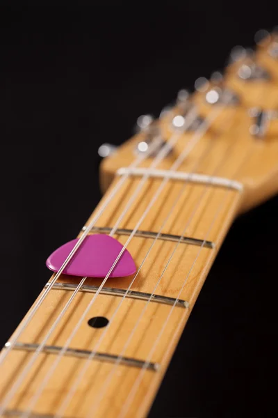 Close-up of a guitar neck with pink pick