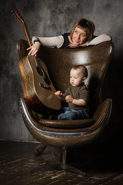 Mother and son on a leather egg-chair with a guitar