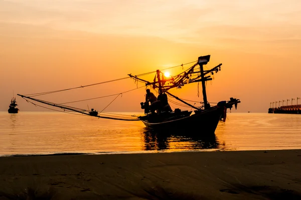 Silhouettes of fishing boats and fishermen at sunrise.