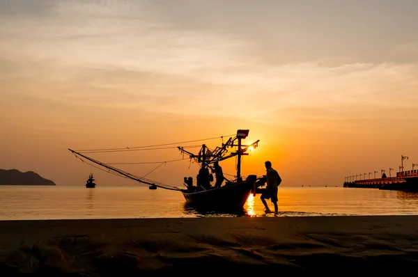 Silhouettes of fishing boats and fishermen at sunrise.