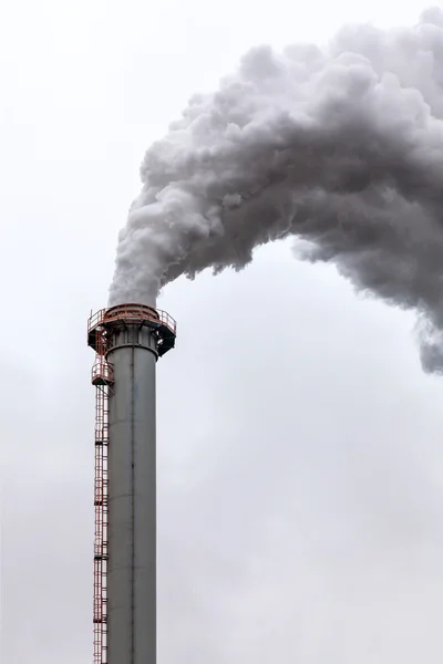Closeup of dirty dark smoke clouds from a high industrial chimney
