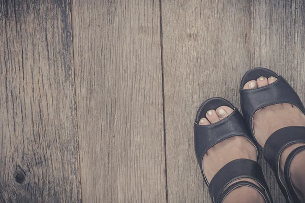 Feet. First-Person view  on rustic wood background.